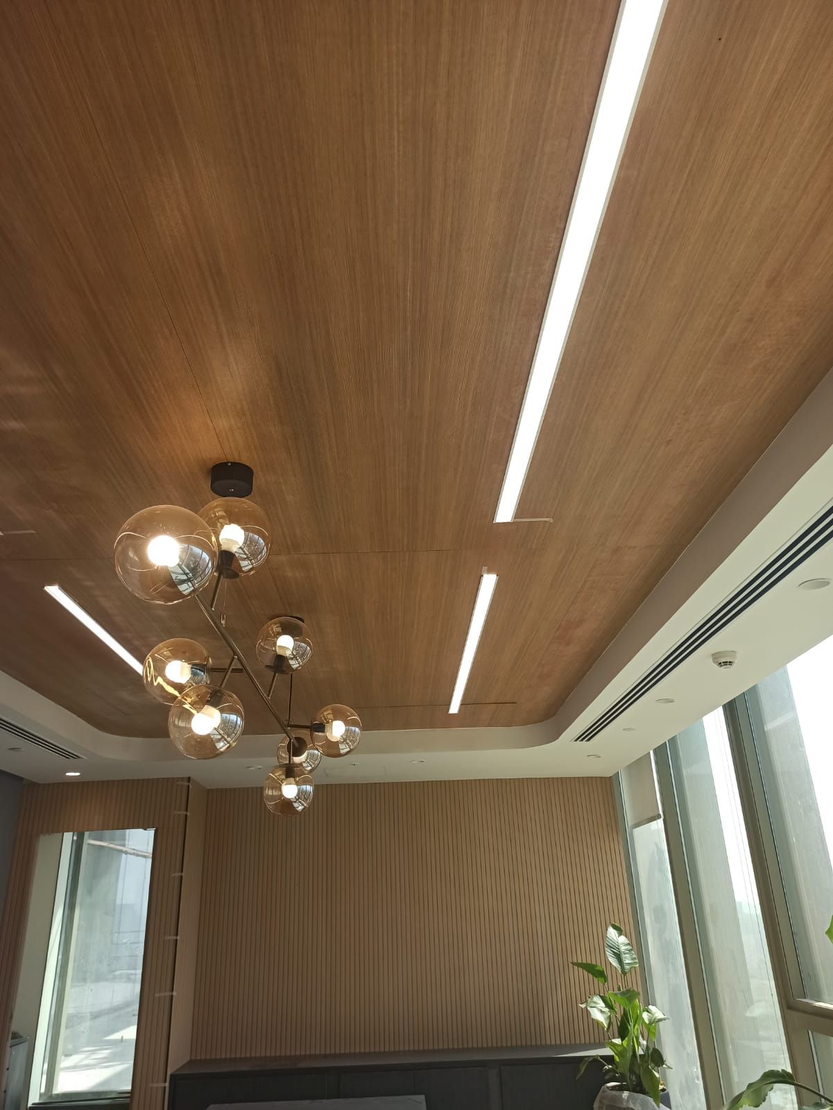 Common area in Hyderabad office with pendant lighting against the micro-perforated wooden ceiling.