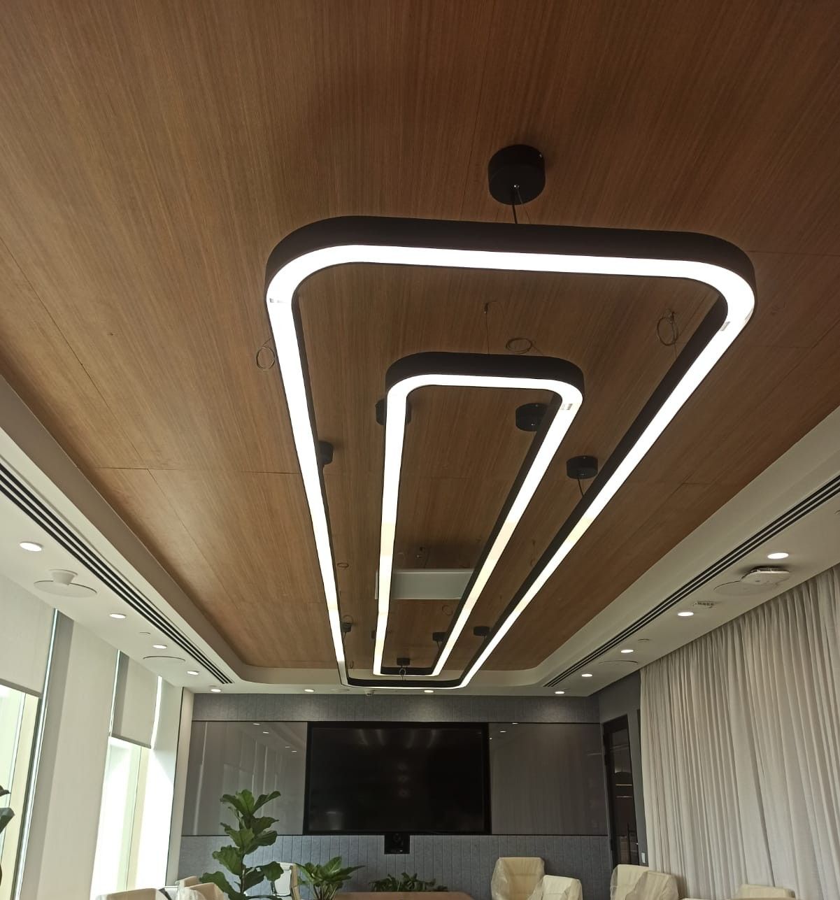 Close view of the curved micro-perforated wooden ceiling profile with linear LEDs flush in the surface.