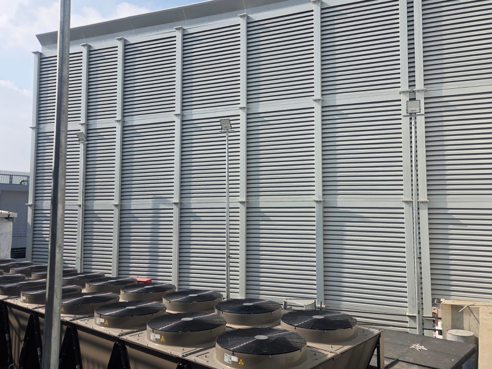 HVAC condensers visible against the completed acoustic louver wall in Bangalore.