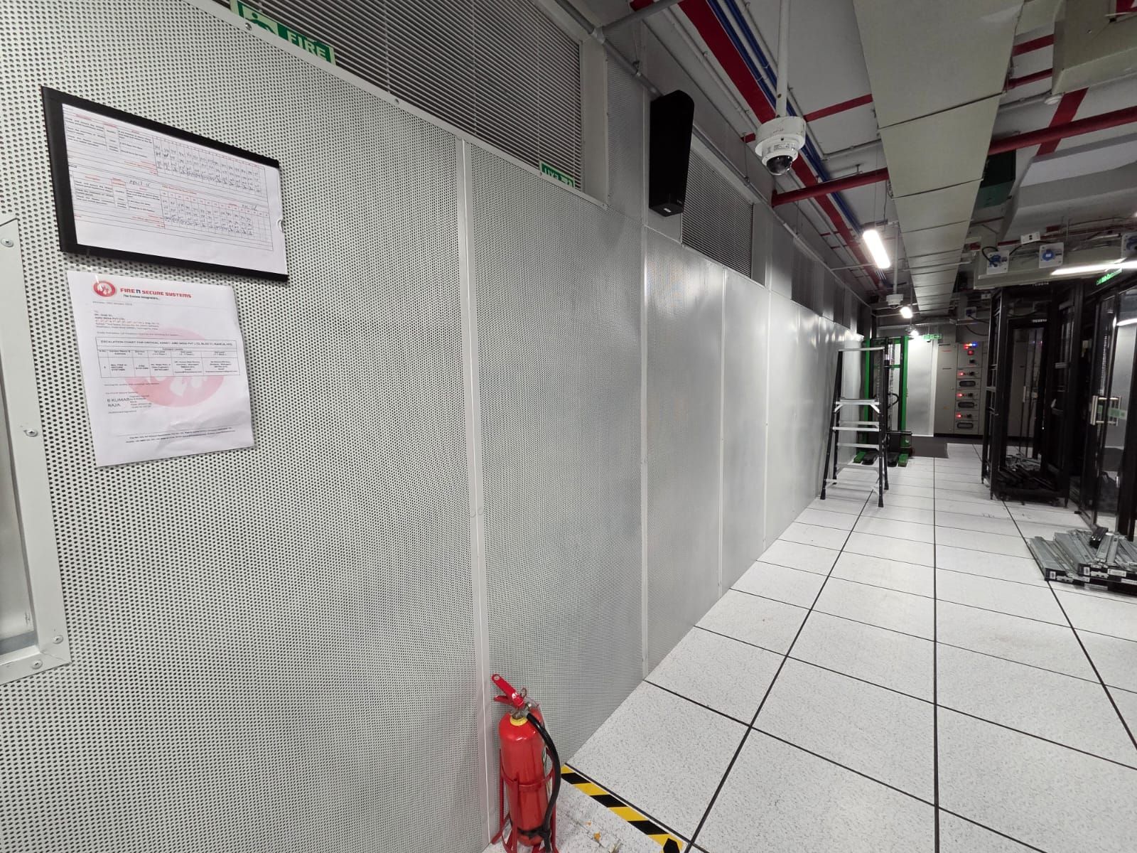 Server room angle showing rack infrastructure alongside the MetPan perforated metal wall surface.